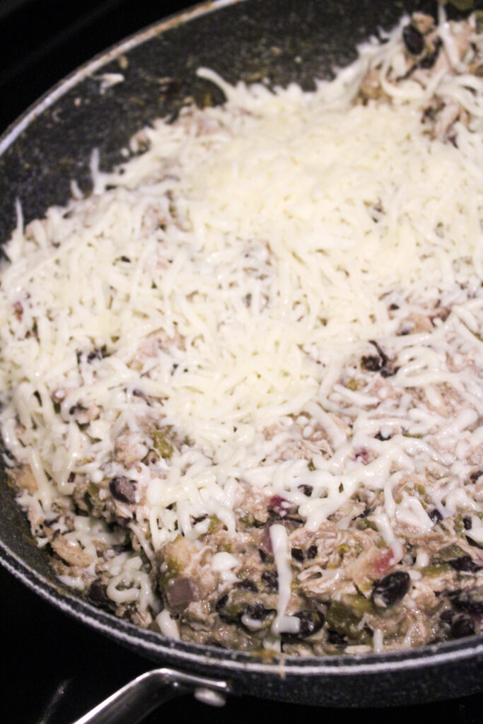 Shredded cheese over an enchilada skillet.