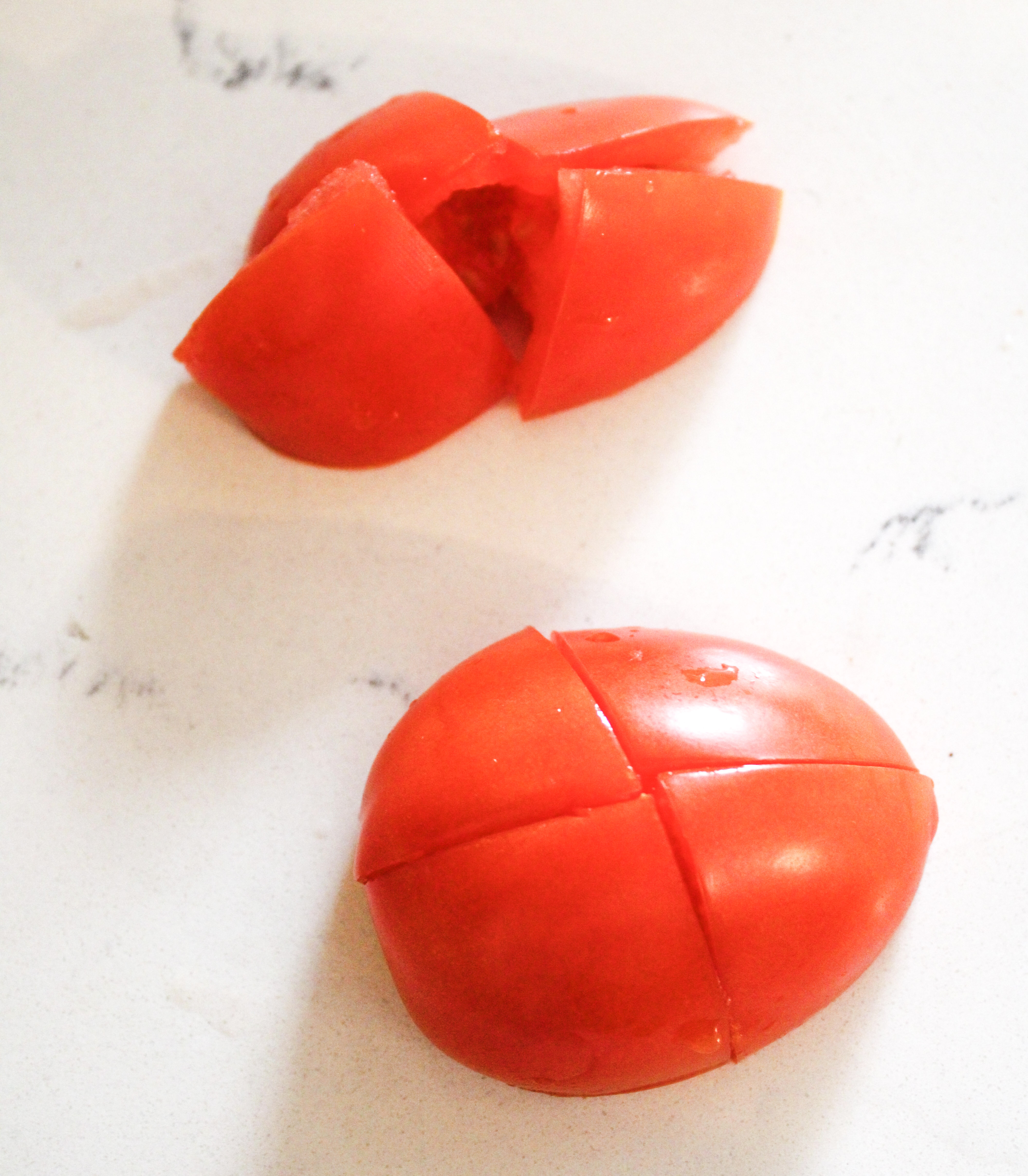A tomato cut into 8 pieces on a cutting board.