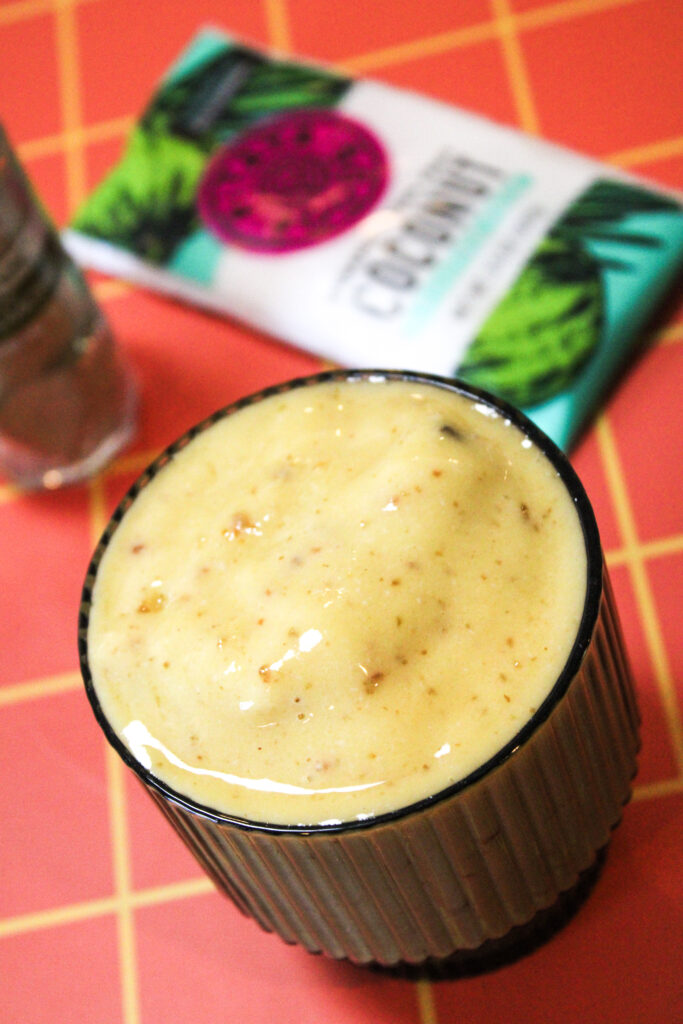A passionfruit coconut smoothie with frozen coconut packet in the background.