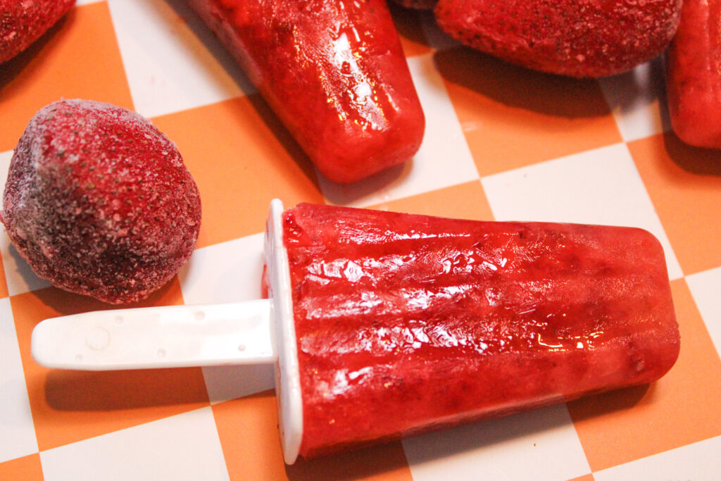 Strawberry popsicle with an orange and white checkered background.