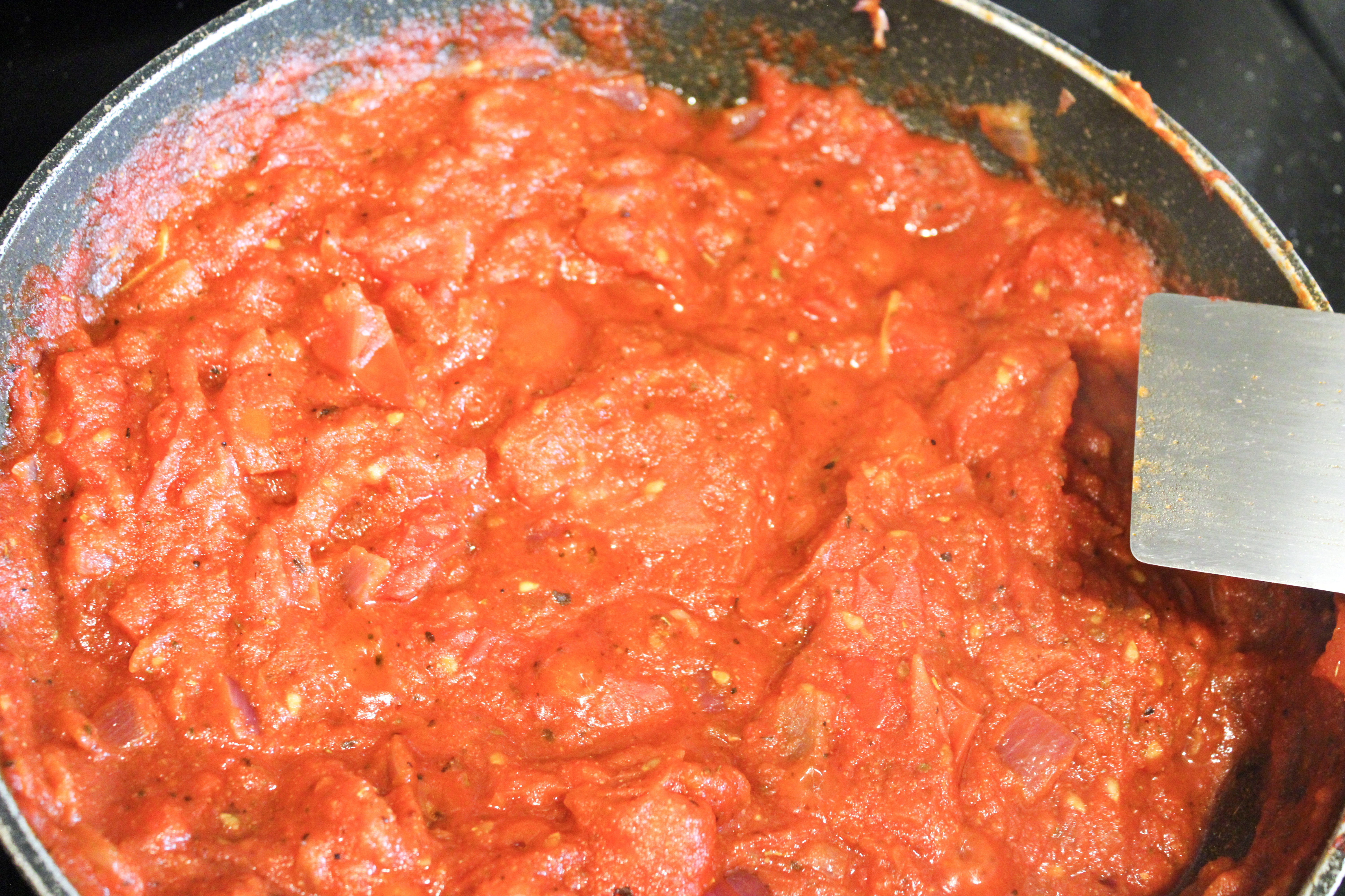 An almost finished marinara sauce cooking in a pan.