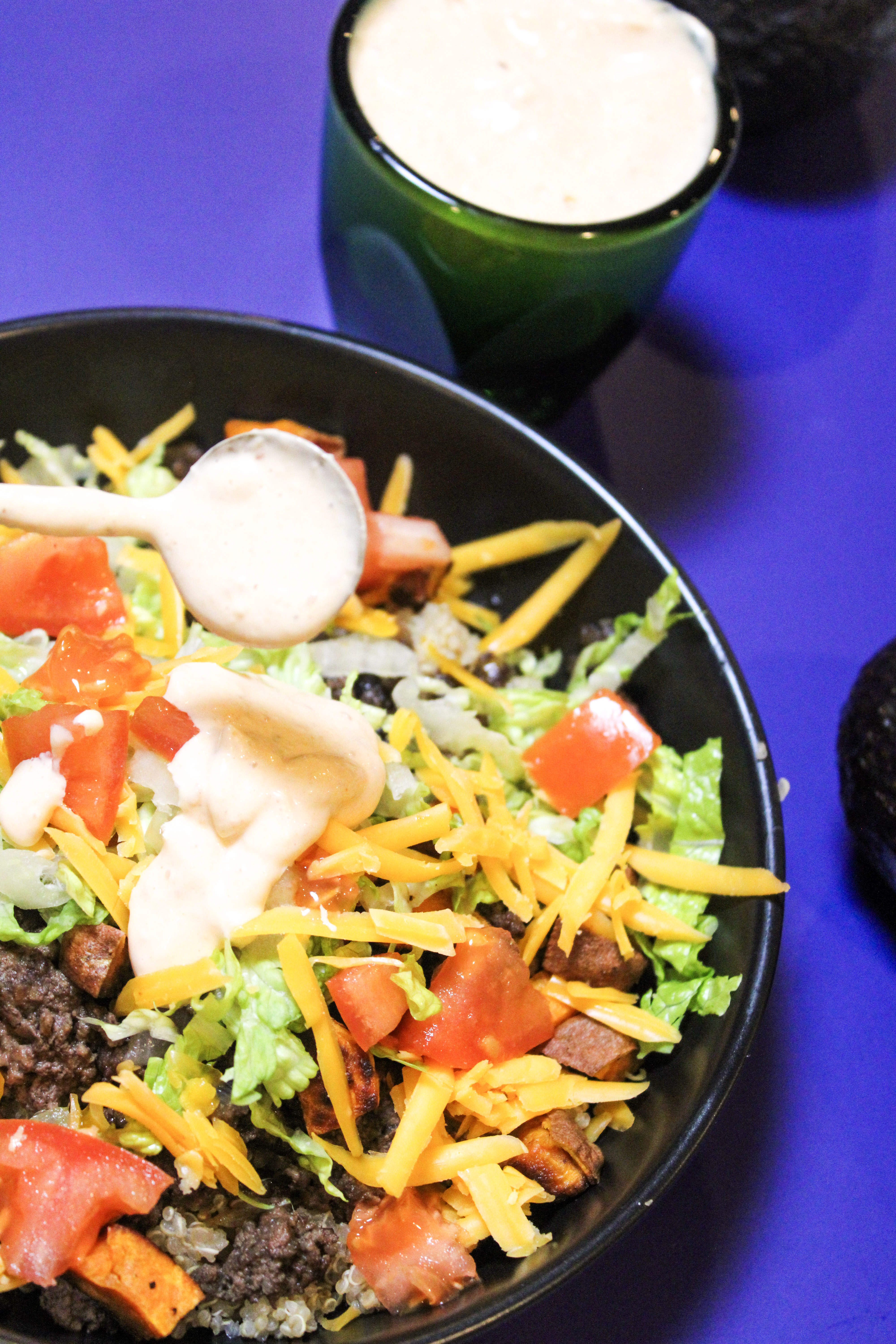 Chipotle aioli being poured over a Mexican style quinoa bowl.