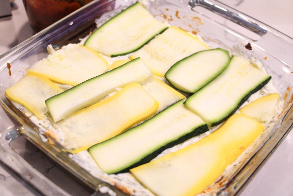 Unfinished lasagna layers with zucchini being the layer thatis on top