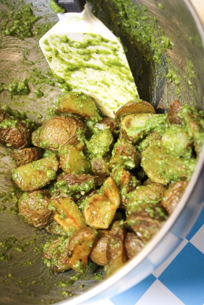 Freshly tossed pesto potatoes in a mixing bowl.