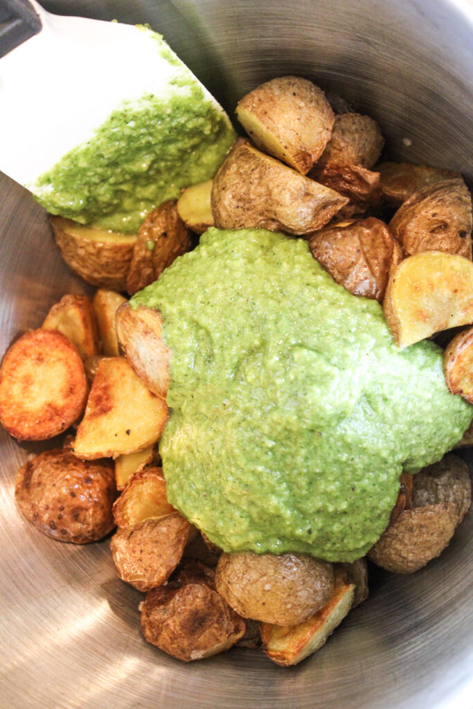 Pesto sitting on top of roasted potatoes, waiting to be mixed in.