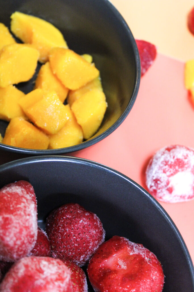 Strawberries and mangoes in their own separate bowls.
